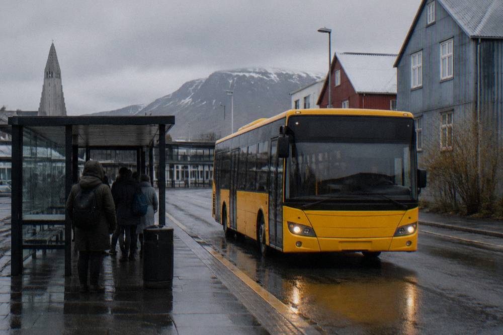 A city bus waiting at a stop on a Reykjavik street