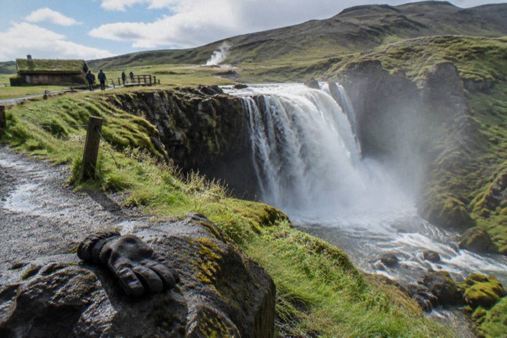 A waterfall pouring over a rock shelf into a misty gorge