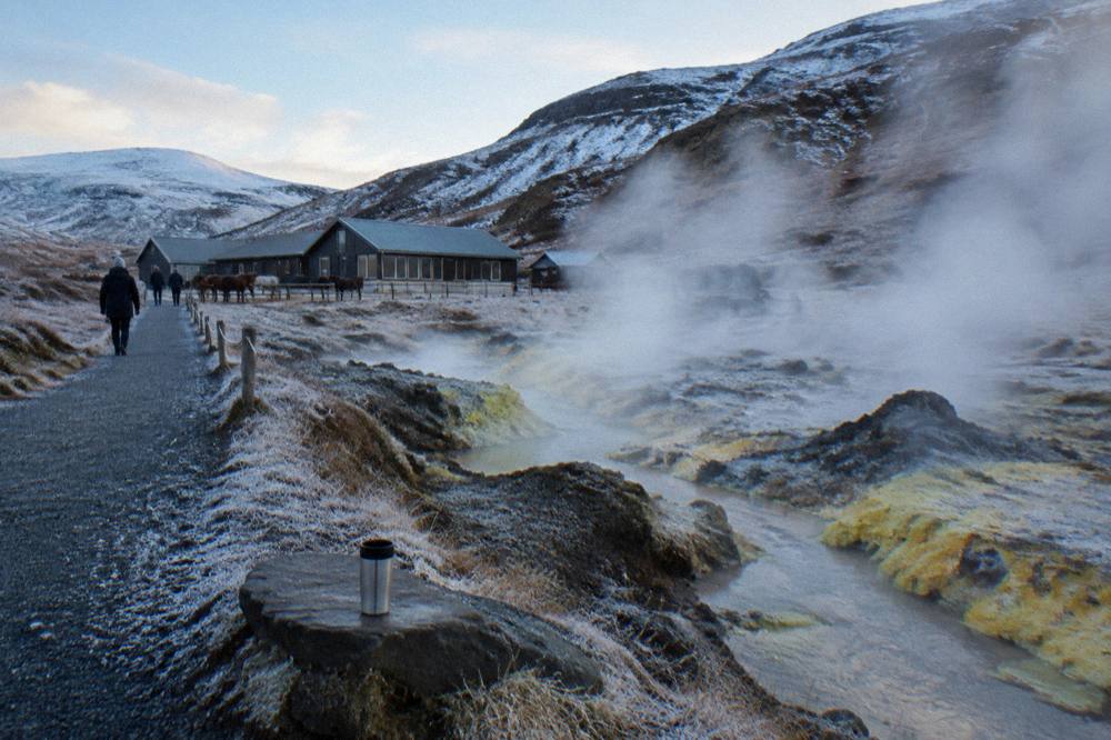 A geothermal field with steaming vents beside a gravel walking path