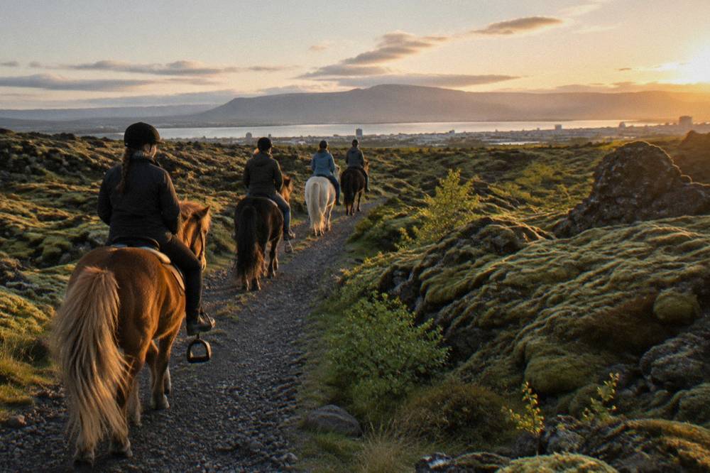 A small group of riders on a gravel trail through mossy lava rock in evening light