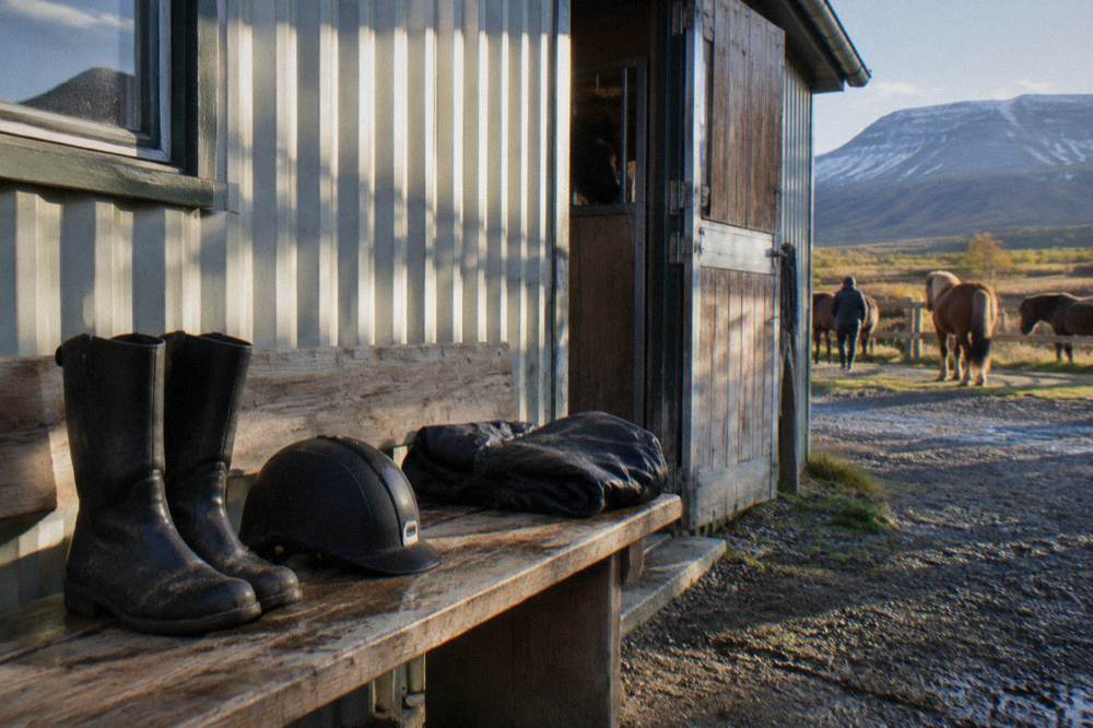 Clean riding boots and a helmet set out on a wooden bench